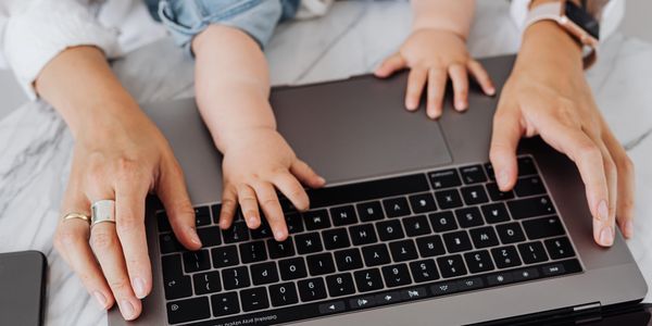 An adult and baby's hands on a laptop keyboard.