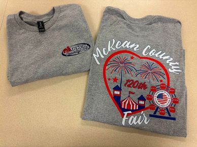 Two gray McKean County Fair T-shirts with colorful design.