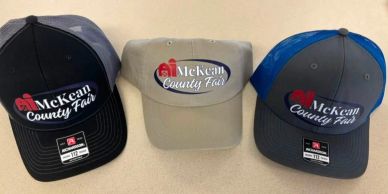 Three McKean County Fair caps in different colors.