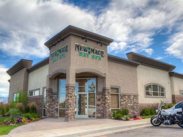 Exterior of New Image Day Spa with stone and stucco facade under a cloudy sky.