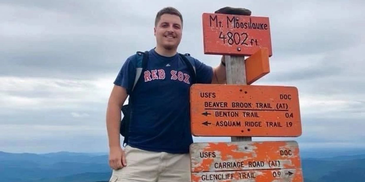 Man standing next to a Mt. Moosilauke trail sign.