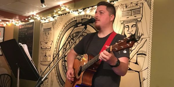 Man singing and playing guitar on stage.