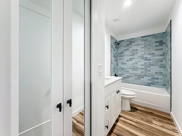 Modern bathroom with blue tile, white vanity, and wood floor.