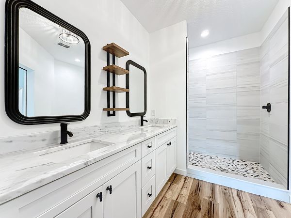 Modern bathroom with double sinks and walk-in shower.
