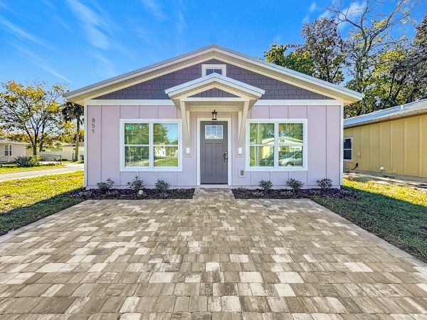 Small house with a paved driveway and a gray door.