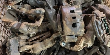 A pile of rusty, used automotive brake calipers in a metal cage.