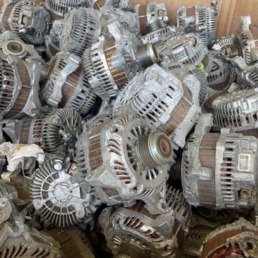 Box filled with used car alternators piled together.