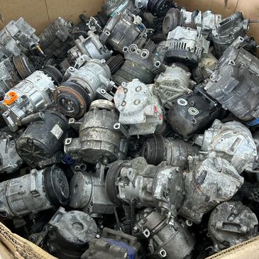 A large box filled with used automotive air conditioning compressors.