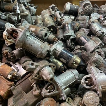 Box filled with used automotive starter motors.