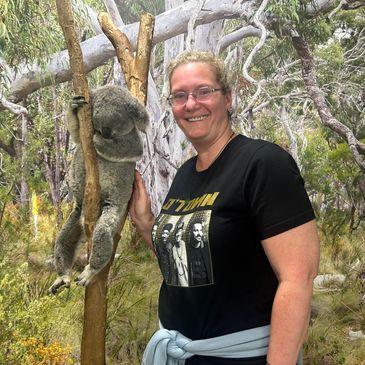 A woman smiling next to a koala