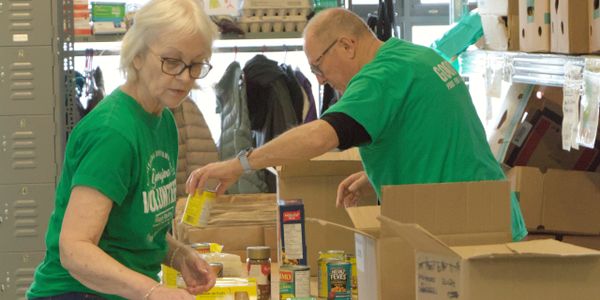 Two volunteers packing food in a community pantry.