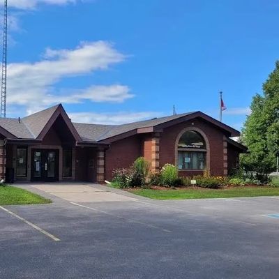 Brick building under blue sky with a parking lot in front.