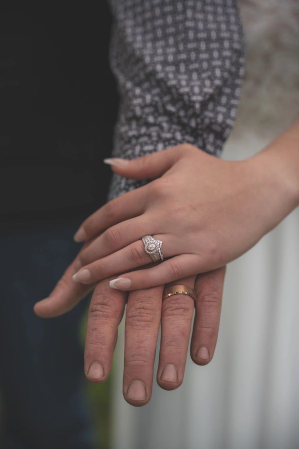 Close-up of hands with wedding and engagement rings symbolizing a couple's bond.