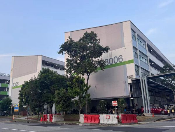 Two large buildings numbered 3006 with surrounding trees and barriers.