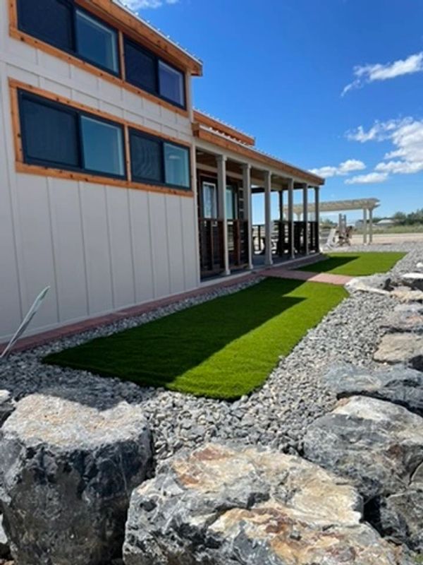 Rock walls and turf in Farr West, Utah in front of a tiny house cabin