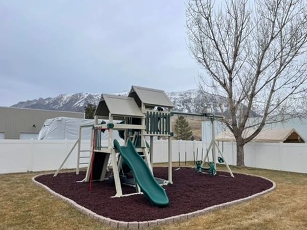 Patiova Concord Playset with turbo slide and glider swing on mulch play area in Farr West, Utah