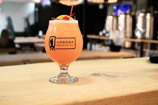 Colorful craft cocktail garnished with fruit, placed on the bar top.
