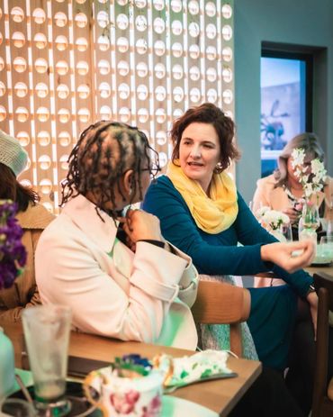 Two women engaged in a lively conversation at a cozy café.