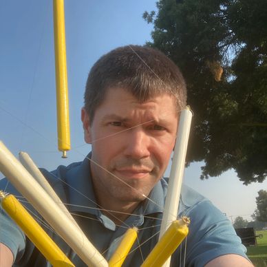 Steve Thomas Outside, Looking at the Camera from Behind a Tensegrity Model