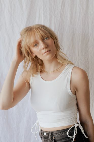 Girl in front of a white back drop with blonde hair and blue eyes