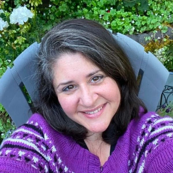 Smiling woman in purple sweater outdoors.