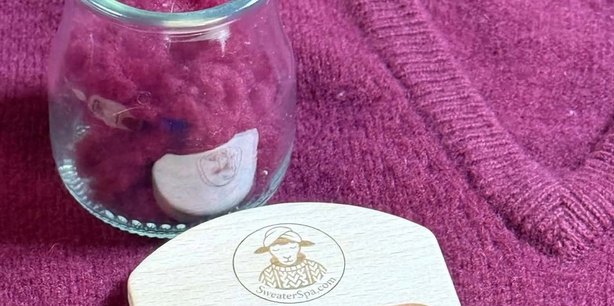 Glass jar and wooden tool on maroon knitted fabric.