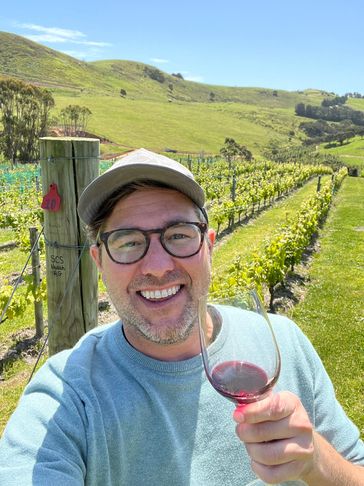 Man enjoying a glass of red wine in a sunny vineyard.