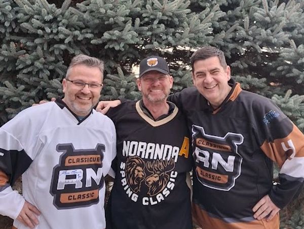 Three men in hockey jerseys smiling outdoors in front of trees.