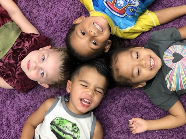 four kids are lying on a carpet 