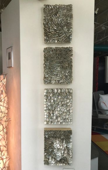 Four decorative panels with metallic circular patterns arranged vertically on a white wall.