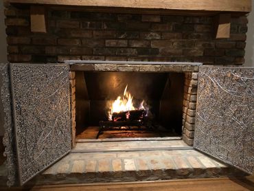Custom fireplace screen created by Tamara Robertson with view of fire.