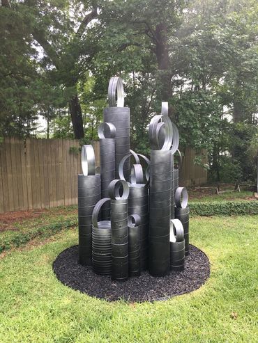 Abstract outdoor sculpture made of stacked black and silver rings.