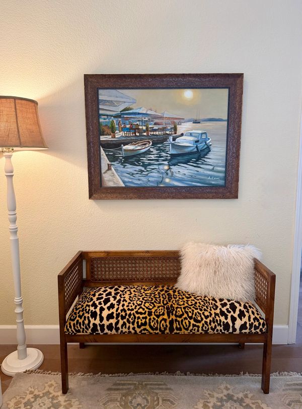 Cozy corner with leopard-print bench and boat painting.