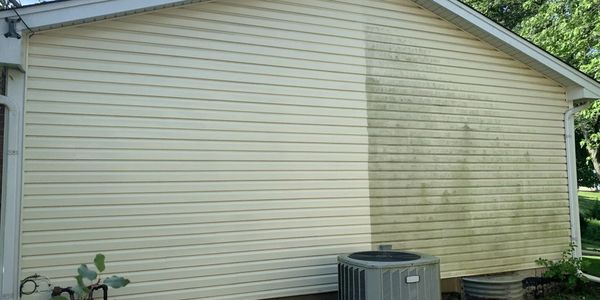 House with half of siding washed and half dirt to show the cleaning results from house soft washing.