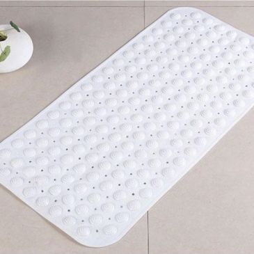 White rectangular anti-slip bath mat with suction cups on tiled floor.