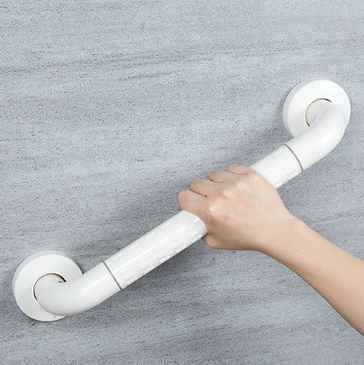 Hand gripping a white safety grab bar on a gray wall.