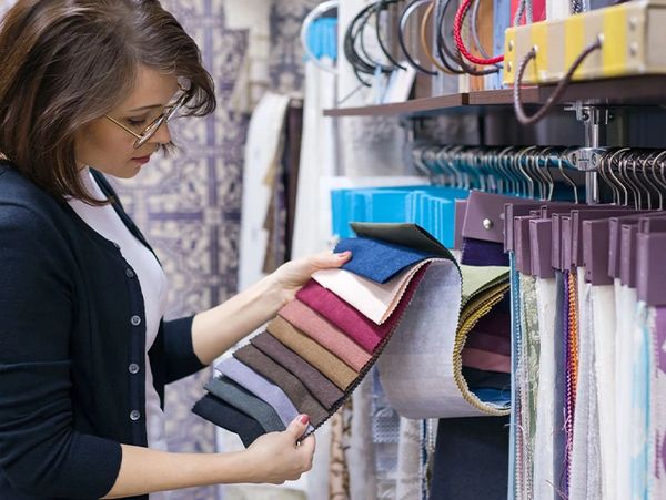 Woman examining fabric samples in a textile store.