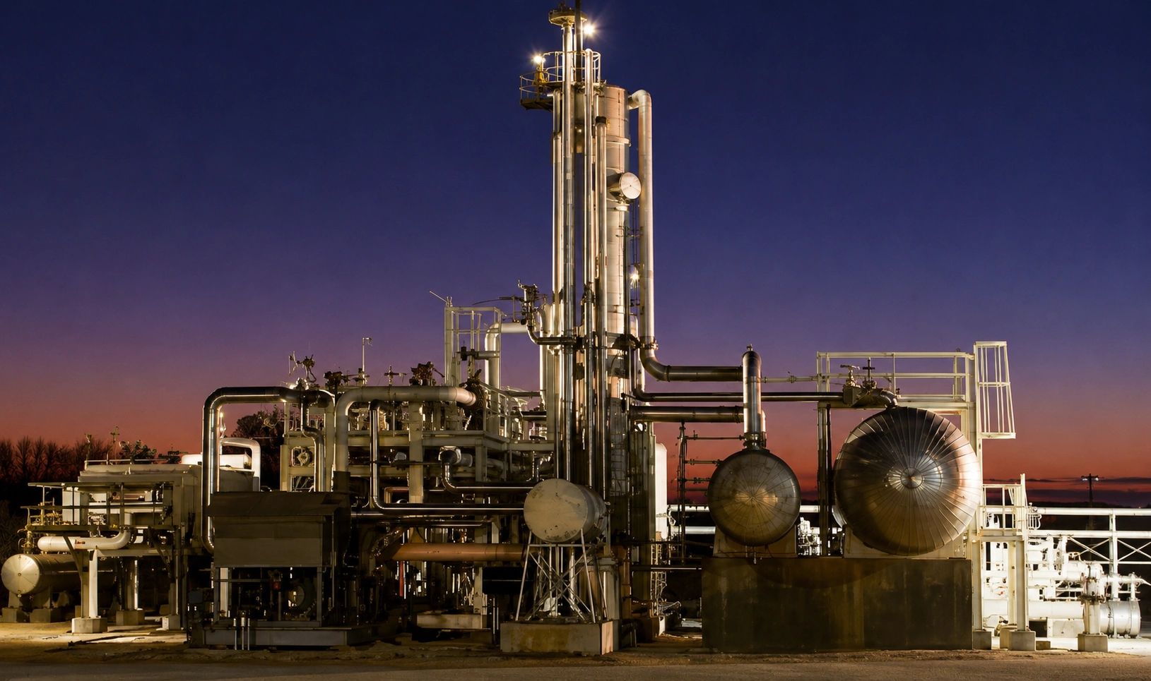 Industrial plant with pipes and tanks at dusk.