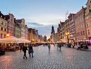 Evening view of a lively cobblestone street with colorful buildings and people walking.