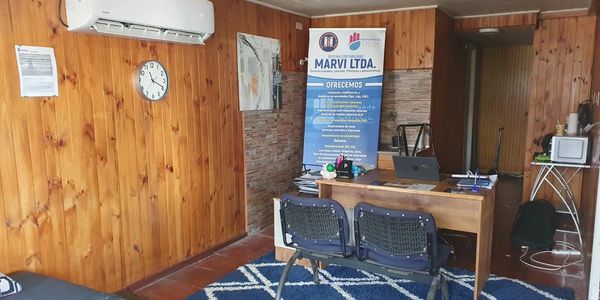 Small office with wooden walls, desk, and two chairs.
