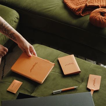 Tangerine branded leather accessories on a green couch.