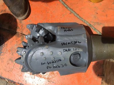 Close-up of a mechanical drill bit with handwritten markings on it.