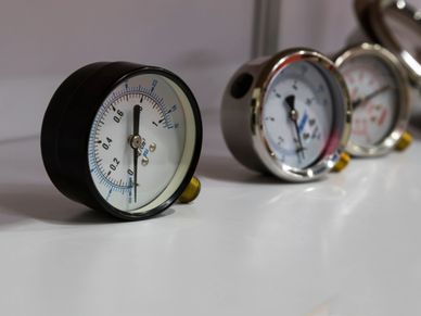 Close-up of pressure gauges lined up on a white surface.