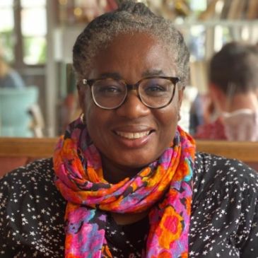 Smiling woman wearing glasses and a colorful scarf.