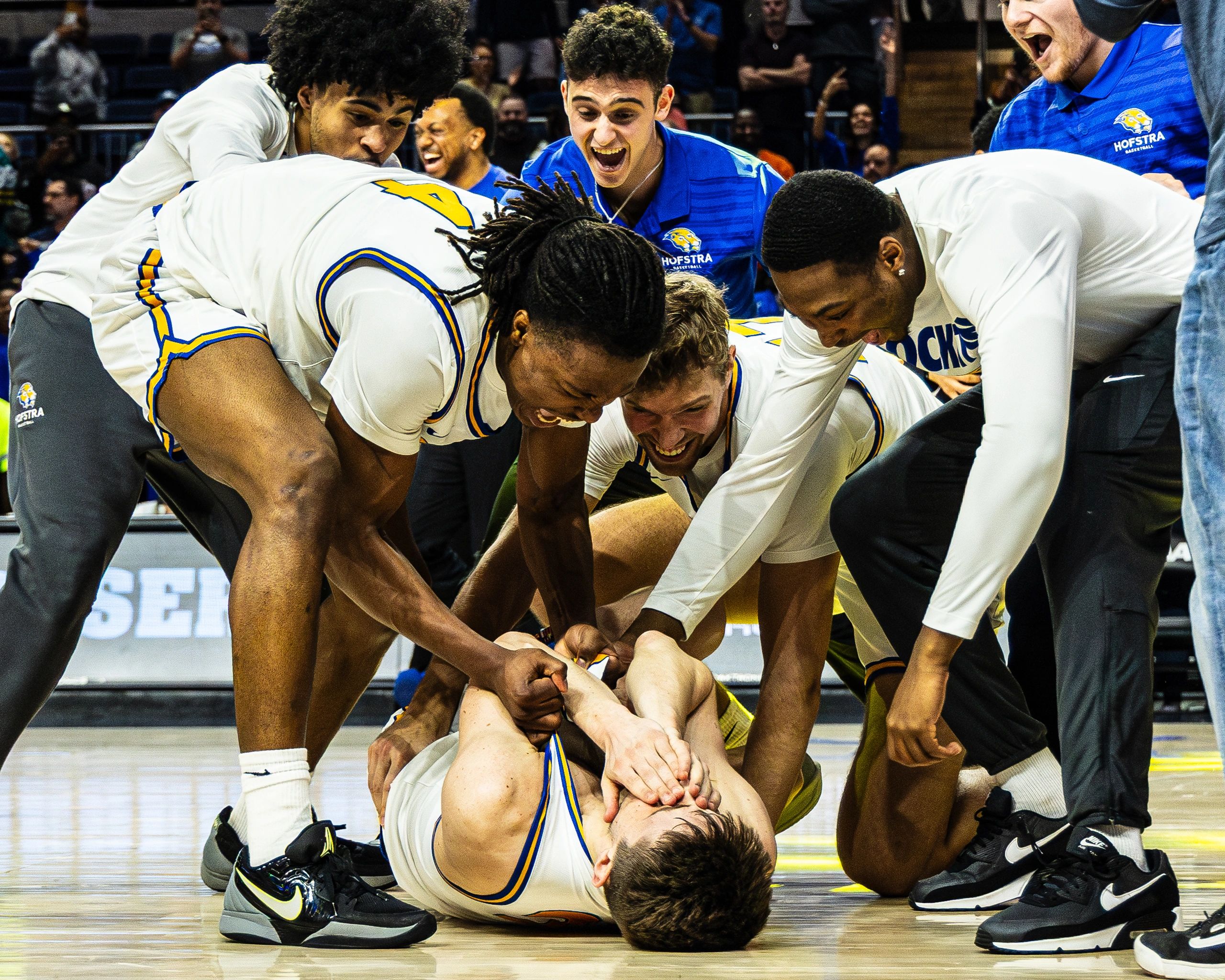 Basketball players joyfully celebrate a teammate on the court.