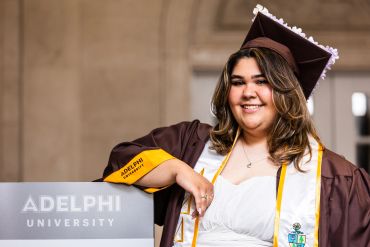 Smiling graduate in Adelphi University regalia.