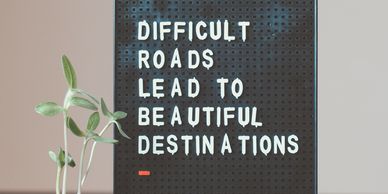 Black pegboard with letters that read “difficult roads lead to beautiful destinations”