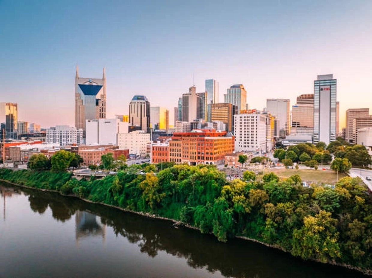 City skyline with river and greenery at sunset.