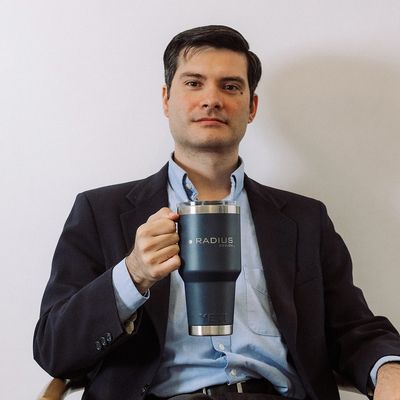 Man in suit holding a large Radius-branded tumbler.