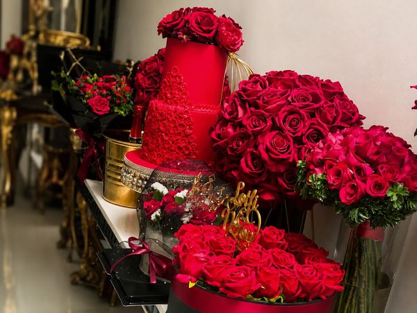 Luxurious red roses and a red cake on an elegant table.